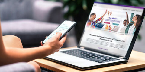 person on a phone and laptop view a website